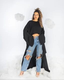 - What it is: A black, oversized cape-style top with dramatic wide sleeves paired over a cropped top, shown with distressed blue jeans and nude heels.
- Audience and styling: Appears designed for women; the look is casual-chic with a bold, fashion-forward vibe suitable for streetwear or a trendy outfit.
- Notable attributes: Solid black color; long, voluminous batwing sleeves; cropped length of the inner top; paired with high-waisted, ripped light-wash jeans; nude open-toe heels. Material looks lightweight and drapey for the outer layer.