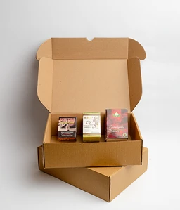 - What the product is: An open cardboard shipping box containing three small, colorful boxes arranged in a row.
- Apparent audience and styling: Unisex presentation; plain, minimalist packaging with natural brown cardboard, suggesting a simple, unpackaged-in-box gift or sampler format.
- Notable attributes: Visible small white, purple, gold, and red boxes with printed designs; sturdy corrugated cardboard; no branding visible on the outer box. The overall look is compact, unbranded, and ready for receipt or gifting.