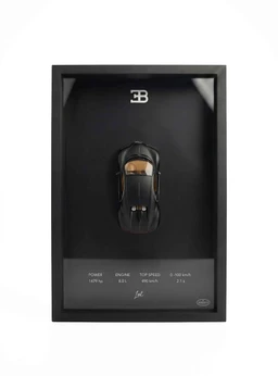 - A miniature black Bugatti Chiron model mounted inside a rectangular black display frame with a clear front. The top center features a small emblem; a small car model sits in the middle of the frame, with technical readouts and a signature-like mark at the bottom.
- Audience: unisex (display piece suitable for collectors and general decor).
- Notable attributes visible: black color with a glossy finish, compact car model, framed presentation, and printed specifications on the lower panel. No branding beyond the generic “Bugatti” model presence.
