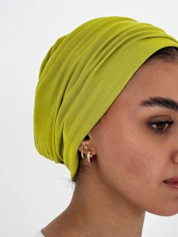 - What the product is: A lime-green twisted or wrapped headscarf/head wrap, shown styled as a turban with a layered wrap effect.
- Apparent audience: Women, based on styling and jewelry (earring) and head wrap design.
- Notable attributes visible: bright lime/acid green color, soft ribbed fabric with a double-layer wrap look, snug fit around the head, no visible branding. Earrings shown for styling, but focus is on the head wrap. Material appears to be a stretchy knit or jersey.