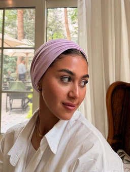 - What the product is: A lilac double-layer cotton Lycra head wrap/scarf styled on a woman.
- Apparent audience: Women (adult) judging from the model and styling.
- Notable attributes visible: Soft lilac color, seamless fabric with a smooth, gathered wrap style forming a layered look around the head; paired with a white button-down shirt for a clean, modest look; no visible branding. Materials appear to be cotton Lycra with a stretchy, comfortable finish.