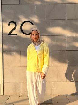 - A woman wearing a light, airy chemise styled in bright yellow with cream or off-white wide cuffs and collar peeking from under a white long-sleeve layer. The outfit includes loose, high-waisted cream or ivory wide-leg pants and a matching headscarf, creating a soft, modest silhouette.
- Apparent audience: unisex-leaning women’s fashion.
- Notable attributes: vibrant yellow top, pale cream pants, oversized, relaxed fit, long sleeves with contrast cuffs, headscarf, light-wash or ivory color palette, minimal pattern with a clean, elegant look.