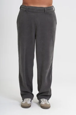 - What it is: A pair of grey casual pants with a straight leg and belt loops, shown from the waist down to the shoes.
- Intended audience: Likely unisex or men's, judging from the fit and styling on a male torso.
- Visible attributes: Medium-dark grey fabric, flat-front design, zip/button closure, belt loops, side pockets, and a relaxed, slightly oversized fit. The pants are paired with casual sneakers, emphasizing a relaxed, everyday style.