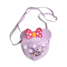 A small kids crossbody bag shaped like a cute animal head with a lavender body and ears. It features a pink polka-dotted bow, a yellow center, and a clear front panel filled with colorful glitter; the word “LUCKY” is printed on the top. The adjustable strap is lavender, making this item clearly intended for children (likely girls) with playful, sparkly styling and sequin/glitter accents.