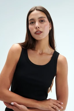 - What the product is: A black sleeveless tank top with a scoop neckline.
- Intended audience: Women's; modeled on a female adult.
- Notable attributes: Solid black color, simple fitted silhouette, medium-width shoulder straps, smooth knit fabric, minimal styling with natural makeup.