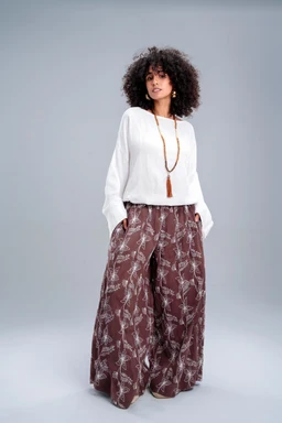 - What it is: A brown wide-leg pants set with a long, flowy silhouette. The pants feature a light, vine-like pattern and a relaxed, drapey fit; the top is a white, long-sleeve knit or blouse with a slightly loose, comfortable cut.
- Intended audience: Women's (based on styling, cut, and model presentation).
- Notable attributes: Brown patterned wide-leg pants, white long-sleeve top, lightweight, bohemian/soft casual style, visible necklace accessory. Material appears to be lightweight fabric for the pants and a knit/blouse fabric for the top.