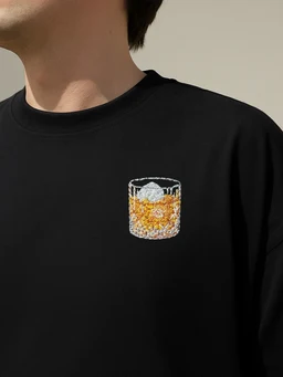 - What the product is: A black crew-neck T-shirt featuring a small graphic of a glass with drink on the chest.
- Apparent audience: Unisex (model appears gender-neutral; styling is simple and versatile).
- Notable attributes: Black cotton fabric with a small, colorful print of a short glass filled with an amber-colored beverage and ice on the left chest. Simple, minimalist style without visible branding.