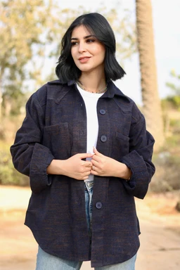 A navy wool shirt jacket with a relaxed, slightly oversized fit, worn open over a white top. The model appears to be a woman, suggesting a women's or unisex audience; styling is casual and cozy with rolled sleeves and a crisp collar. Notable features include the navy wool fabric, large front patch pockets, and oversized button-front placket.