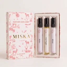 - What it is: A makeup/fragrance sample kit labeled “MISKA” with three small roller or roll-on vials inside a pink-and-white forest/animal-themed box. The box lid shows “DISCOVER YOUR SCENT” and “MISK A” with a delicate pastel design; three slim vials are visible in the inner tray, each with a black cap and light-colored labels.
- Intended audience: Unisex or general audience based on neutral pastel styling and compact travel-size presentation.
- Notable attributes: Light pink and white color scheme, botanical/animal motif, three mini perfume/essential oil roller vials (eau de parfum) with black caps; compact 10 mL box set style.