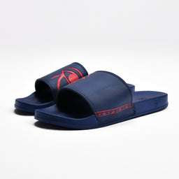 A pair of blue slide sandals with an open-toe, two-strap design. Appears sized for men or unisex, based on the straightforward, sporty cut and broad strap styling. Notable features include dark blue color, red stitched accent along the strap and side, and a flat, cushioned sole for casual, warm-weather wear.