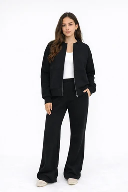 - What the product is: A women's Everyday Comfort Set consisting of a black bomber-style zip-up jacket paired with wide-leg black pants. The model wears a white top underneath, completing a monochrome lounge-ready look.
- Apparent audience and styling: Designed for women; relaxed, casual, and comfortable fit with a minimalist, chic streetwear vibe.
- Notable attributes: Solid black color, soft-looking fabric with a slightly oversized, relaxed silhouette; bomber jacket with a zipper and cuffed sleeves; wide-leg, high-waisted pants; light-colored top and neutral shoes to contrast the all-black set.