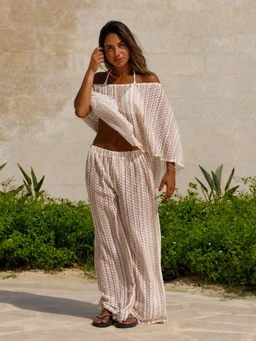 - What the product is: A women’s matching two-piece set consisting of an off-the-shoulder top and wide-leg pants in a light, airy fabric.
- Apparent audience: Women (based on the model, cut, and styling).
- Notable attributes: Sand beige color with a delicate, small print; off-the-shoulder top with a wide, ruffled/slightly flutter sleeve; elasticized or relaxed fit pants with a drawstring or elastic waist; lightweight, flowy material suitable for warm weather; beachy, coastal vibe.