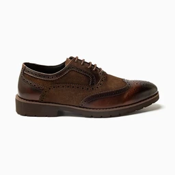 A brown leather brogue-style oxford shoe with perforated detailing along the toe cap, sides, and heel. Appears designed for men, featuring a classic lace-up closure, a slightly rounded toe, and a low-profile crepe-like sole. Notable materials include smooth and suede textures in dark chocolate brown with tonal stitching.
