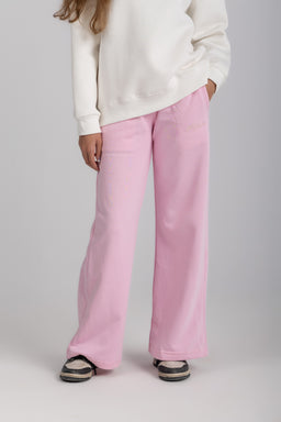 The item is a pair of pink straight-leg sweatpants worn by a female-presenting model. Visible styling suggests a relaxed, casual fit with an elastic waist and wide-leg silhouette, paired with a white sweatshirt for a cozy loungewear look. Notable attributes include the soft pink color, cotton-blend appearance, and the wide, straight-cut leg with a casual, oversized vibe.