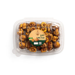 - A clear plastic clamshell container filled with roasted nuts, arranged in a neat, circular pattern. The nuts appear to be a mix of almonds, cashews, and possibly hazelnuts, glazed for a shiny finish.

- Target audience: unisex; suitable for snacking by adults and kids alike. Visible label in the center with Arabic text and a brown-taupe color scheme, indicating a mixed nut product. The snack’s color palette is warm golden-brown, with the nuts showing a roasted hue and a glossy coating.