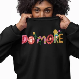 - Description: A black oversized crewneck sweatshirt featuring the word “DO MORE” in colorful, patterned lettering across the chest. The fabric appears soft and thick, with a relaxed, roomy fit as shown by the model pulling the neckline up.
- Audience and styling cues: Intended for a unisex or both men’s and women’s casual streetwear audience, demonstrated by the oversized silhouette and bold graphic text.
- Notable materials and attributes: Black fleece/garment-dyed fabric, with multicolored, decorative letters that include floral and geometric patterns; long sleeves and a crew neckline.