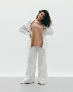 - What the product is: A relaxed two-piece set featuring a color-block style with a sleeveless peach-toned top layered under a white oversized jacket and matching white wide-leg pants. The outfit appears coordinated for lounge-to-casual wear.
- Intended audience: Women (based on the model, styling, and fit).
- Notable attributes: Materials imply a soft, knit-like top with a light, breathable outer jacket and wide, flowing pants. Color palette centers on peach and white with a casual, athleisure vibe; overall look is oversized and comfortable, with flat sandals completing the styling.