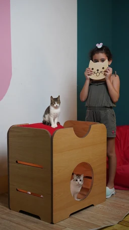 - What it is: A wooden two-level cat bed/hideaway with cut-out openings and a tunnel-style design allowing a cat to perch on the upper level and access a lower cave.
- Audience and styling cues: Appears unisex and suitable for cats (pets) rather than people; the scene shows a child nearby for scale, suggesting a family-friendly pet product.
- notable attributes: Natural wood finish with smooth edges, a red top surface on the upper level, two side drawers-like openings for a ramp/steps, and a circular entrance on the front for the lower level. The overall style is modern, compact, and pet-friendly.