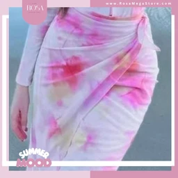 - What the product is: A white fabric wrap skirt or draped sarong-style skirt with a tie detail at the hip, featuring a pink, purple, and yellow watercolor-like tie-dye pattern.
- Apparent intended audience: Women (unisex style but shown on a female model; fits a women's fashion segment).
- Notable attributes visible: Lightweight, soft fabric with a colorful pastel tie-dye print; white base with pink/mauve and yellow accents; wrap-around style with an asymmetric drape and a side tie. Do not assume brand.