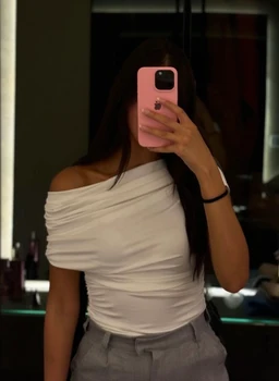 - What the product is: A white off-the-shoulder top with ruching across the bodice, styled on a female model.
- Apparent intended audience: Women.
- Notable attributes: White fabric, form-fitting silhouette, off-the-shoulder neckline, short sleeves with draped ruching and a clean, minimalist look. The top is paired with light gray bottoms for a modern, casual-outing vibe.
