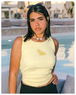 - What the product is: A sleeveless lime-yellow tank top with a small lemon slice graphic on the front. 
- Intended audience: Women's (model is a woman; sleeveless cropped fit suitable for women). 
- Notable attributes: Light, pastel lime color; cropped, fitted cut; round neckline; small lemon graphic; casual summer style. The fabric appears smooth jersey or cotton blend. No visible branding.