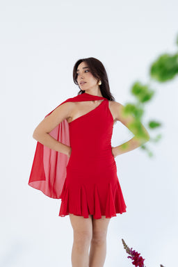 - A short, red halter-style dress with one-shoulder design and a flowing cape detail over the left shoulder, finished with a ruffled hem.
- Intended for women; the model’s styling and fit suggest a chic, dance or party look.
- Notable attributes: bright red fabric, single-shoulder neckline, cape accent, attached cape drape, and a pleated, flounced hem. Material appears lightweight and flowy.