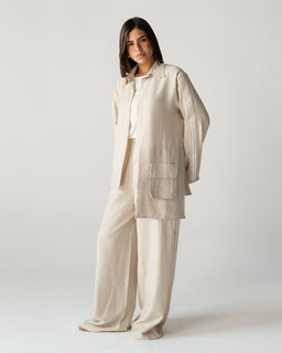 - What it is: A beige linen co-ord set consisting of a longline shirt/jacket and wide-leg pants. The pieces are styled as a coordinated, relaxed-fit suit set.
- Intended audience: Women (based on model styling and fit).
- Notable attributes: Undyed/beige linen fabric with a slightly textured, natural look; oversized, boxy shirt/jacket with large front patch pockets; wide-leg trousers; breathable, casual-suited silhouette.