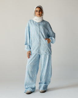 - A light blue, linen pajama set featuring a long-sleeve top and wide, relaxed pants with a loose, comfortable fit. The fabric has a soft, textured linen look with a subtle daisy-like pattern.
- Target audience: women (judging from headscarf styling and relaxed silhouette).
- Notable attributes: sky-blue colour, linen material, matching top and pants, loose fit, full-length sleeves, pockets on the top, wide-leg pants with cuffed hems.