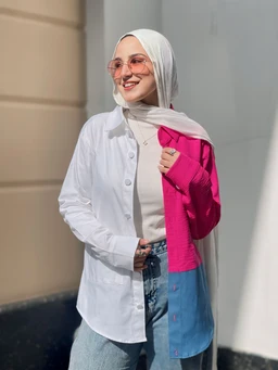 - Product description: A pair of jeans styled with a color-block shirt worn open over a light turtleneck and hijab. The look combines white, pink, and blue panels in a youth-friendly, casual outfit.
- Intended audience: Women (adult) based on styling and modest lifestyle presentation.
- Notable attributes visible: Light-waded denim jeans, color-block oversized shirt with white left side, pink right sleeve, and blue bottom panel, paired with a light beige/cream hijab and pink-titted sunglasses. Overall style is casual streetwear with modest fashion influence.