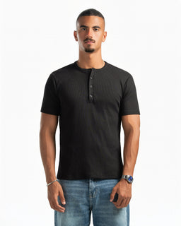 The product is a short-sleeve henley T-shirt in solid black with a three-button placket at the neckline. It appears designed for men, based on the fit, sleeve length, and styling. Notable attributes include a lightweight knit fabric, a crew neck beneath the placket, and a clean, minimal look with a slightly fitted silhouette.