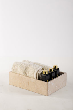 - What the product is: A set of marble-toned towels neatly rolled inside a light stone-colored box, accompanied by a row of small black bottles with gold caps tucked at one end. The arrangement suggests a bath or spa accessory kit.
- Intended audience: Unisex, with a spa or home-bath aesthetic suitable for adults.
- Notable attributes: Soft, textured towels in a neutral beige/cream color; a marble-inspired box; small black bottles with gold caps (likely toiletries). Overall style is minimalist and upscale, with a clean, spa-like presentation.