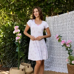 - Description: A light, soft, short-sleeve nightgown or chemise in pale pastel with a small floral print. It has a relaxed, knee-length A-line silhouette and a curved neckline.
- Audience and styling: Appears designed for women, shown on a female model in a casual, home/soft-loungewear setting with a garden background.
- Materials and color: Soft stretchy fabric in a pale white-pink hue with tiny pink floral patterns; delicate, feminine trim on the sleeves and neckline. Notable style: short-sleeve, scoop/rounded neckline, short nightdress length.
