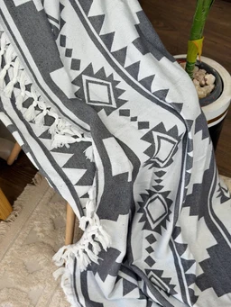 - What the product is: A patterned cover or throw blanket shown draped over a chair with tassel fringe along the edges.
- Apparent audience: Unisex (suitable for both men and women) judging from neutral geometric print and styling.
- Notable attributes: Black and white geometric tribal/aztec print, soft woven fabric, tassel fringe detailing, appears to be a cozy blanket or shawl-like throw.