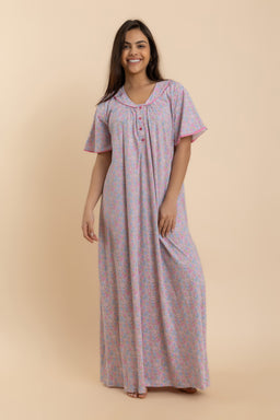 This is a full-length nightdress (dressing gown style gown) in a soft pink floral print. The design features short sleeves, a round neckline with a button placket, and a relaxed, loose silhouette that falls to about ankle length. The fabric appears lightweight and flowy, suitable for women, with a gentle drape and a comfortable, casual style.
